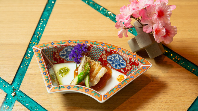 A seasonal dish served on a painted fan-shaped plate